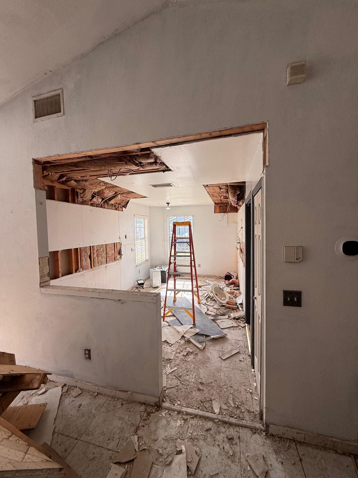 The kitchen stripped back during demolition, with the ceiling opened up and debris across the floor