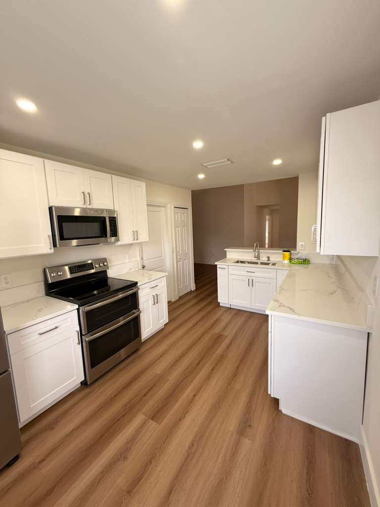White shaker kitchen remodel with a double oven range, quartz countertops and luxury vinyl plank flooring