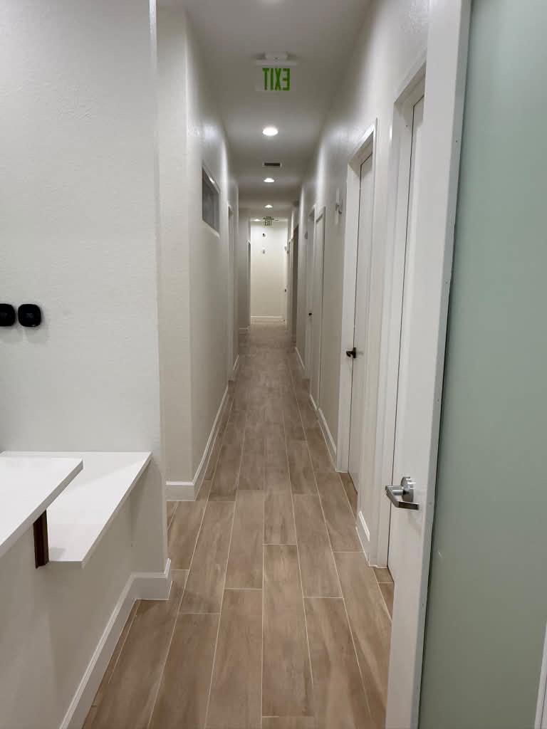Remodeled office hallway corridor with wood-look tile flooring and a row of private office doors