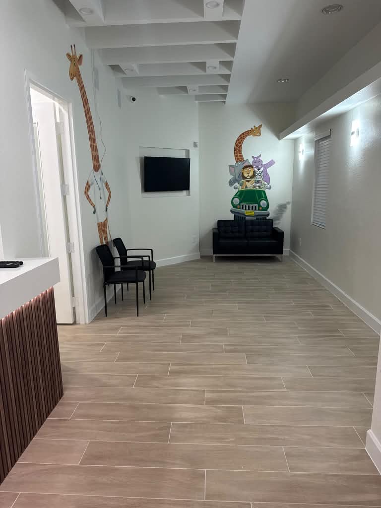 Office waiting lounge with a loveseat, safari-themed wall mural and wood-look tile flooring