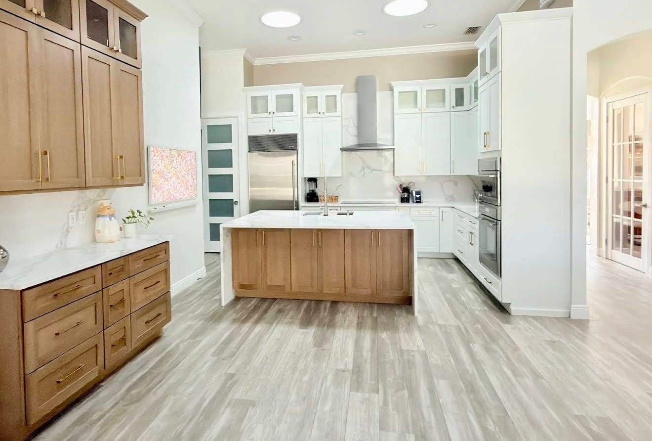 Two-tone kitchen remodel pairing white perimeter cabinetry with a white oak island, marble backsplash and built-in wall ovens